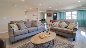 Ein modernes Wohnzimmer mit zwei Sofas, einem Couchtisch und einem Essbereich im Hintergrund.