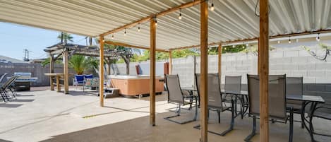 An outdoor patio area with a covered seating area, tables, and chairs.