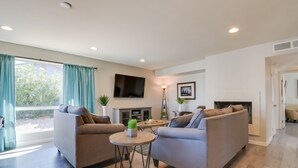 Ein modernes Wohnzimmer mit zwei Sofas, einem Couchtisch, einem Fernseher und einem Kamin.