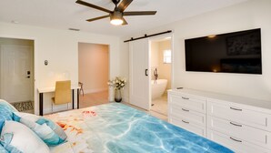 Ein Schlafzimmer mit Bett, Schreibtisch, Stuhl, Badezimmer und Fernseher an der Wand.
