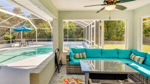 Ein Wintergarten mit Pool, einem türkisfarbenen Sofa und einem Deckenventilator.