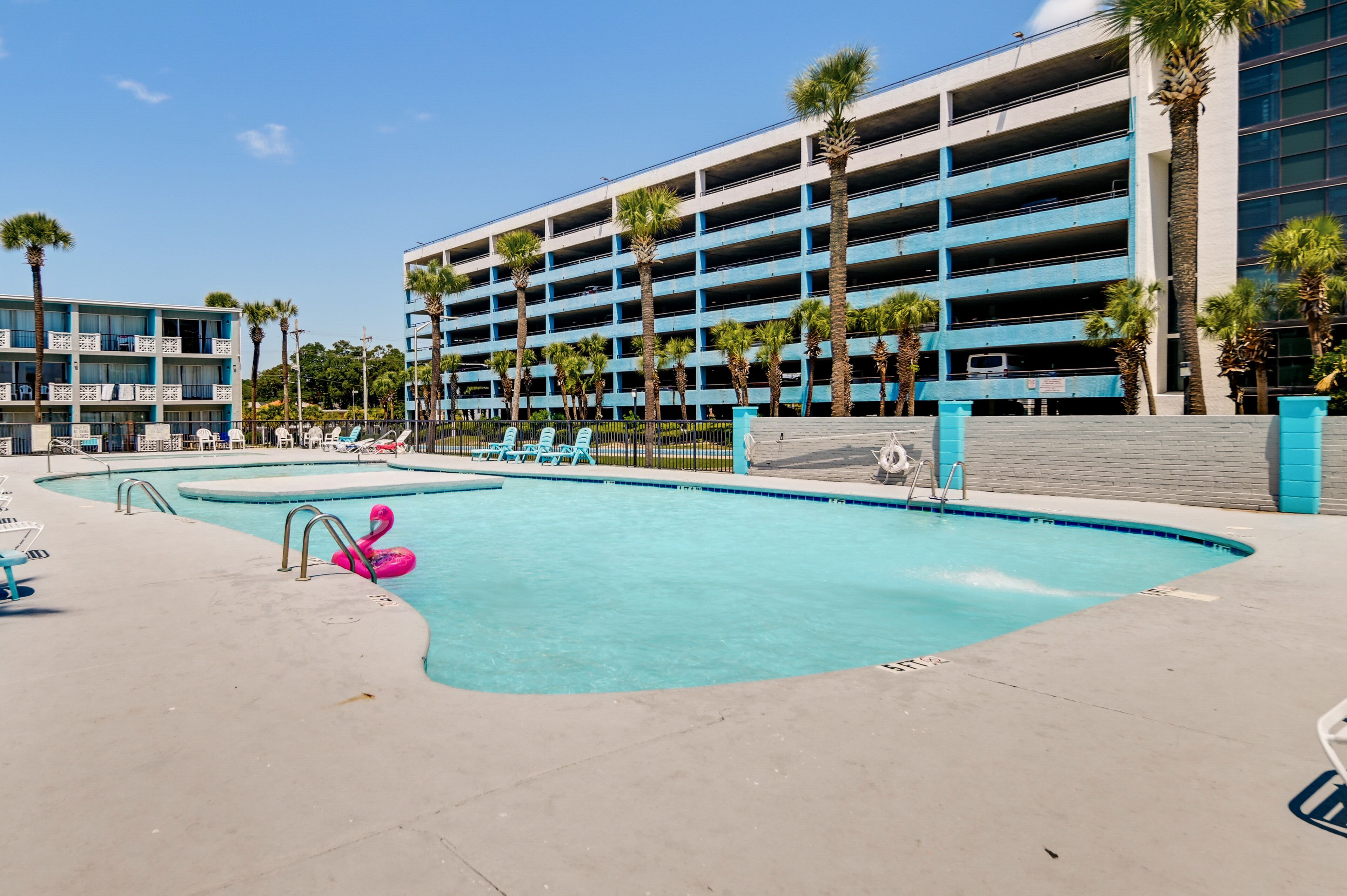 A swimming pool with lounge chairs and a pink flamingo float.
