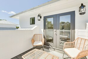 Eine überdachte Terrasse mit Korbstühlen und einer Glastür zu einem Essbereich im Freien.