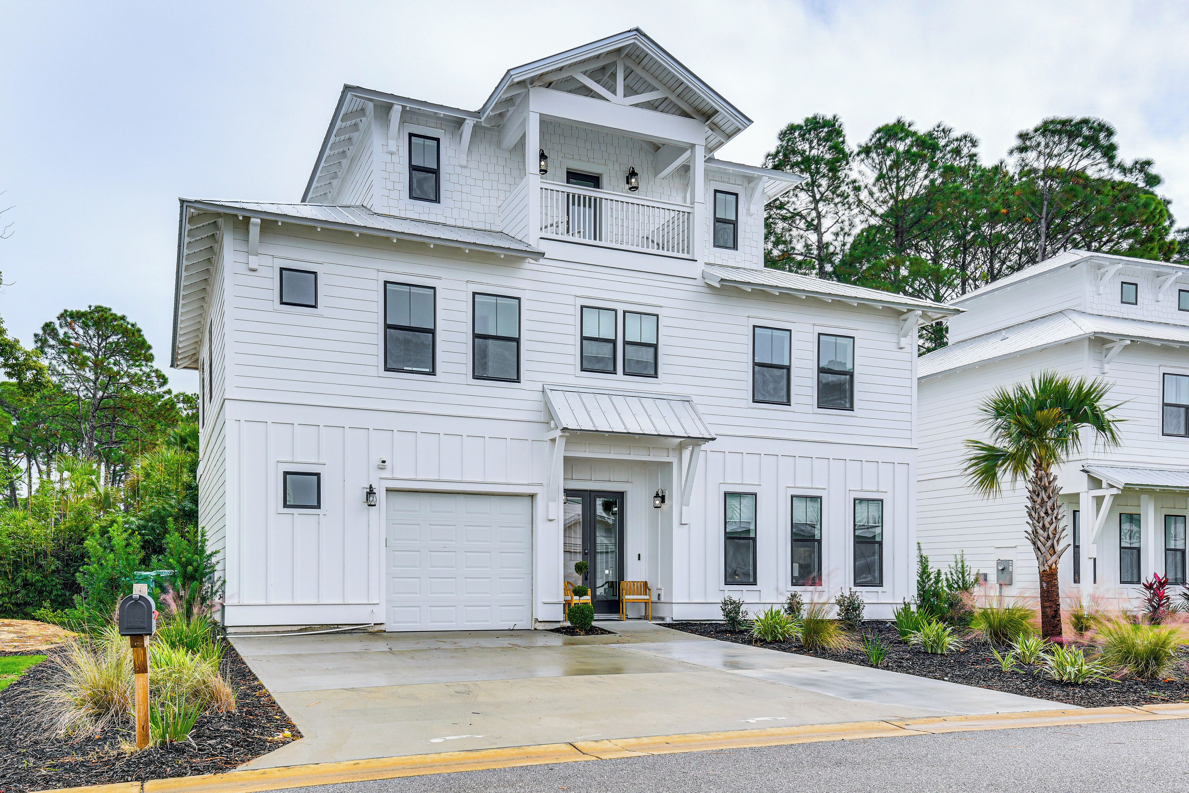 A two-story white house with a front porch, a garage, and a landscaped front yard.