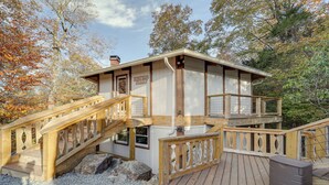 Une cabane en bois dotée d’une terrasse et d’un escalier, entourée d’arbres.
