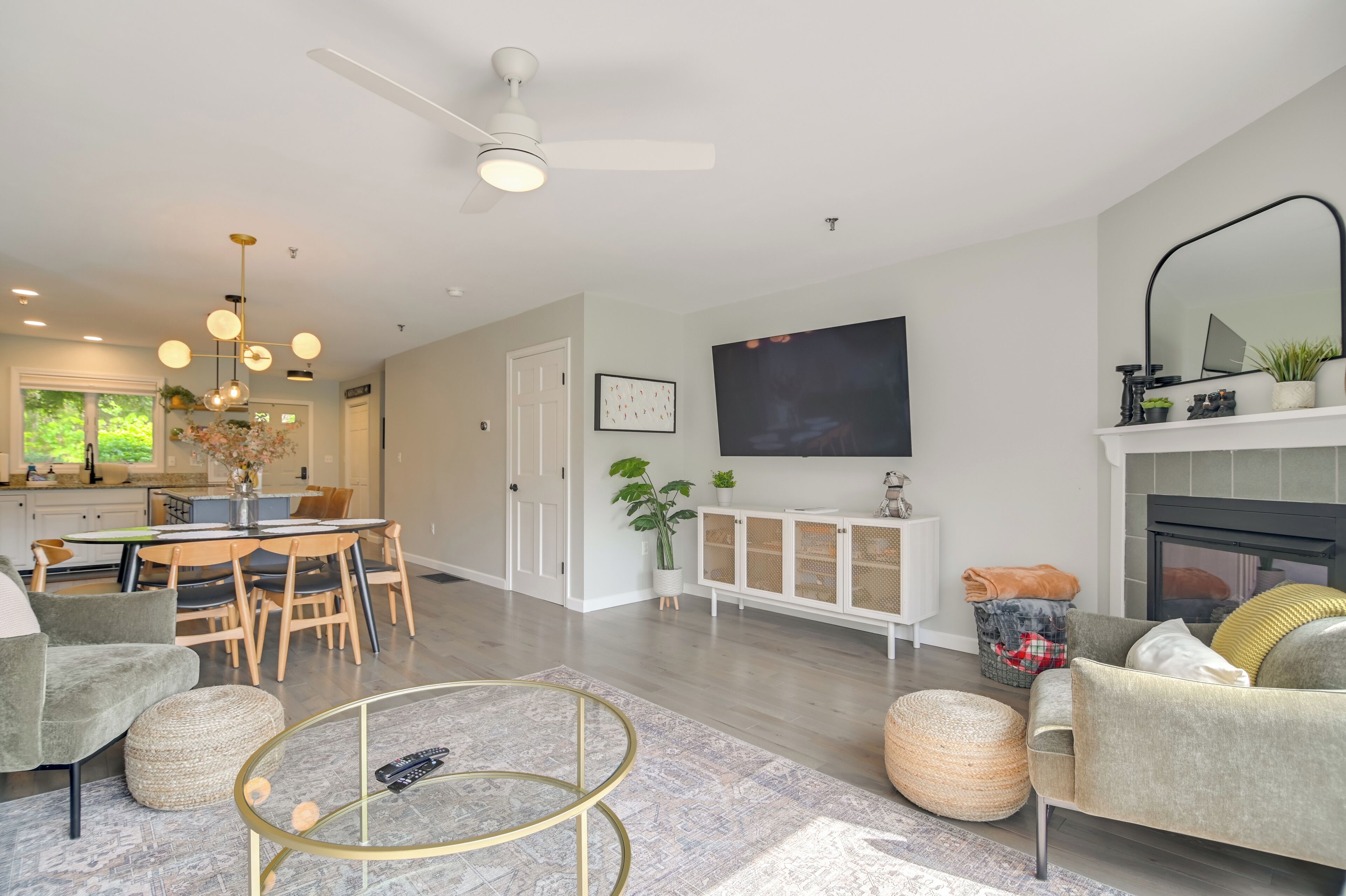 A modern living room with a dining area, a fireplace, and a large TV mounted on the wall.
