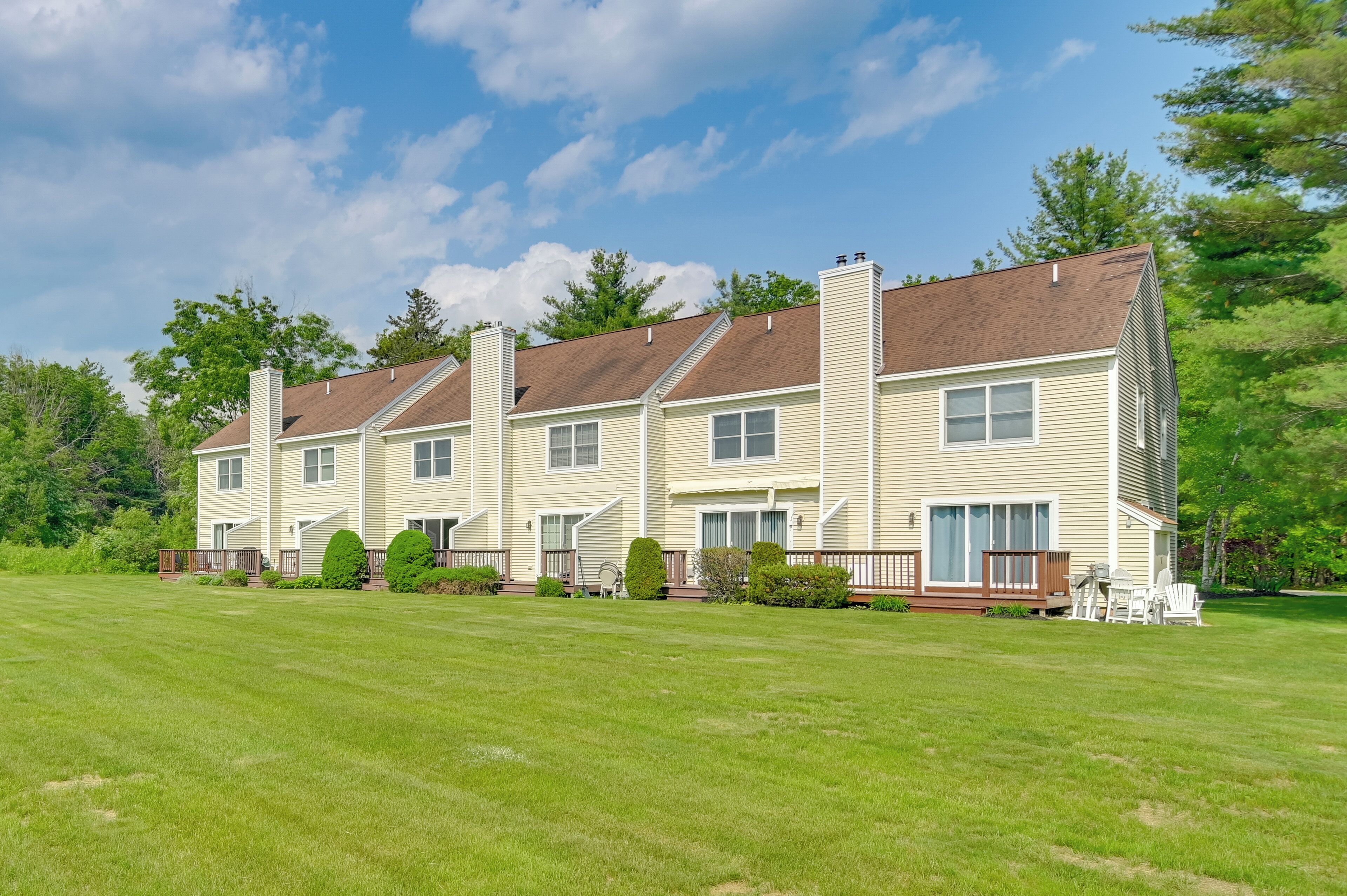 A row of three-story townhouses with a well-maintained lawn and a deck area.