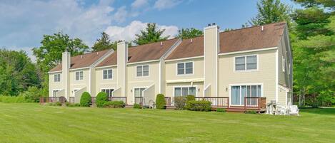 A row of three-story townhouses with a well-maintained lawn and a deck area.