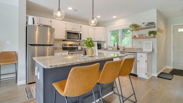 A modern kitchen with white cabinets, stainless steel appliances, a granite countertop, and pendant lighting. - North Conway Home for Fall Adventures (North Conway)