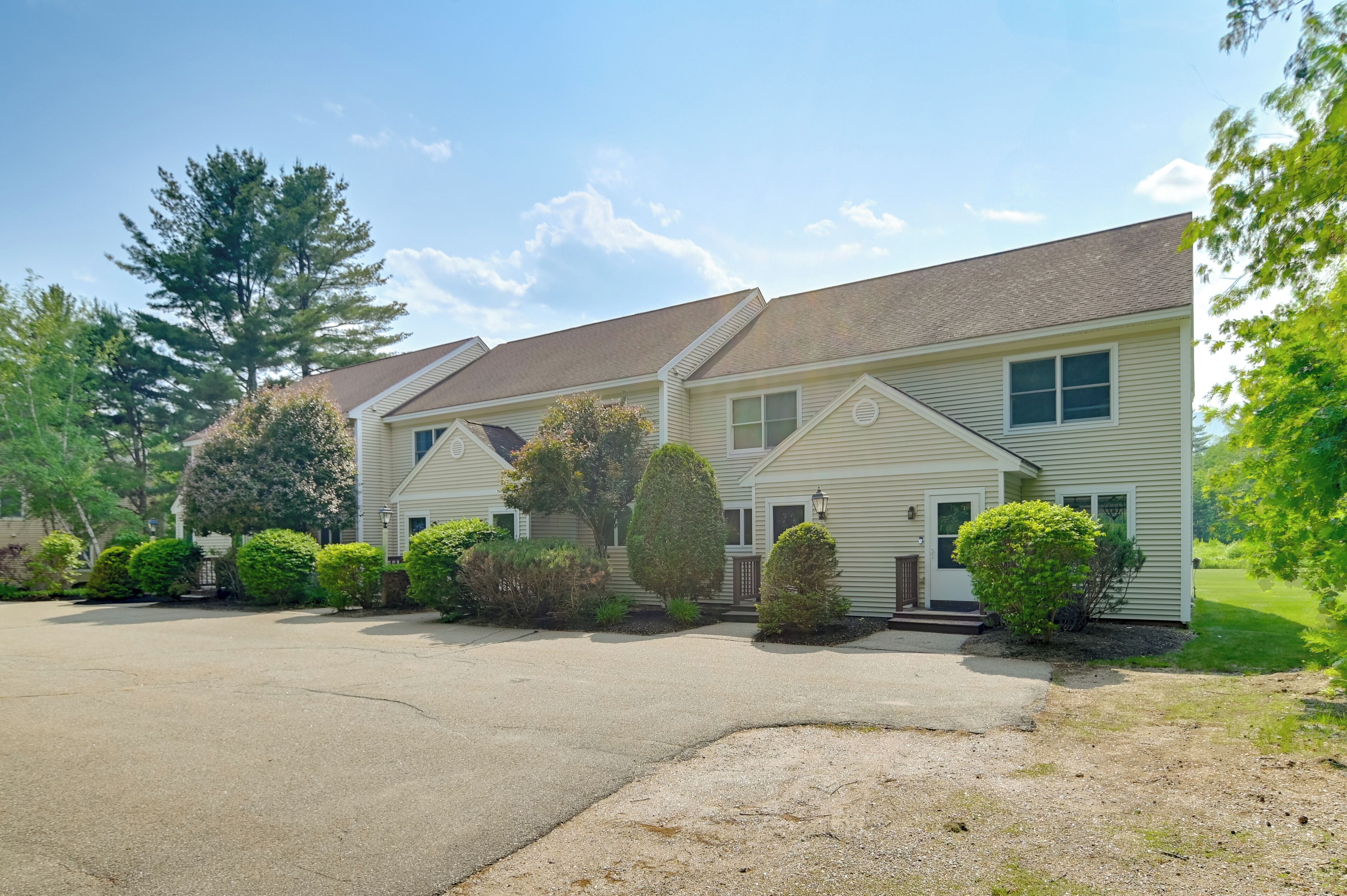 A two-story residential building with a driveway and well-maintained landscaping.
