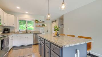 A modern kitchen with white cabinets, granite countertops, and pendant lighting.
