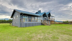 Ein modernes Haus mit einer großen Terrasse, einer Treppe und Blick auf Berge.