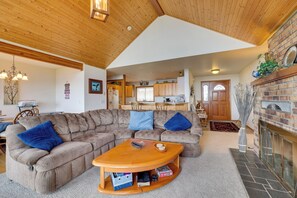A cozy living room with a sectional sofa, a wooden coffee table, and a fireplace. - Oceanfront Port Angeles Home w/ Mountain View! (Port Angeles)