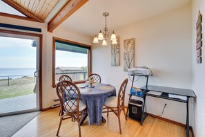 A dining area with a round table, four chairs, a chandelier, and a view of the beach. - Oceanfront Port Angeles Home w/ Mountain View! (Port Angeles)