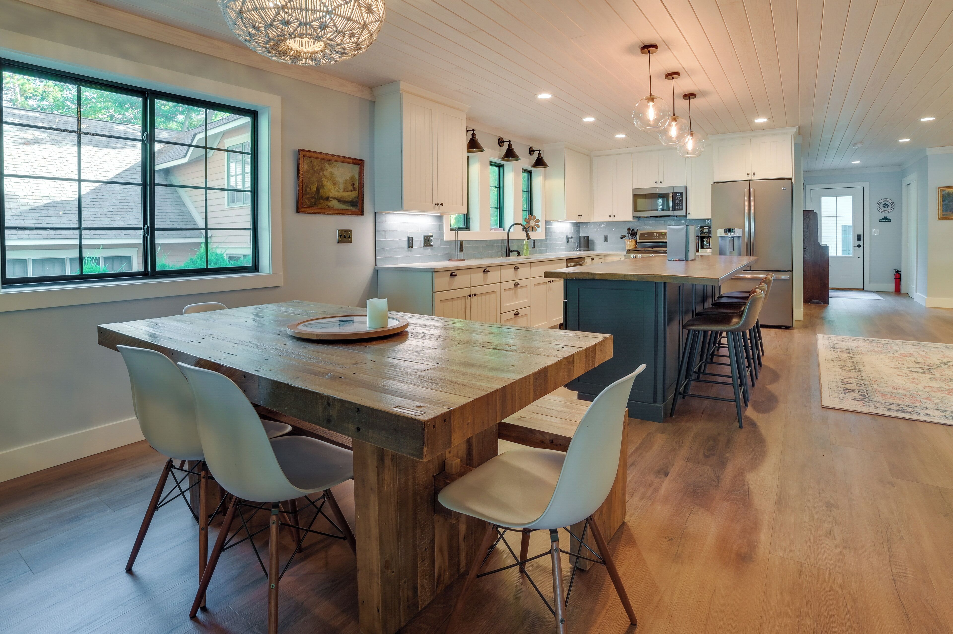 A modern kitchen with a wooden island, white cabinets, and pendant lighting.