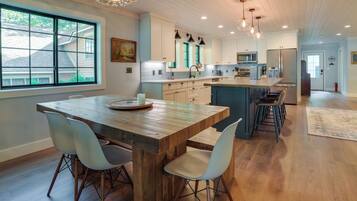 A modern kitchen with a wooden island, white cabinets, and pendant lighting.