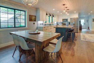 Una cocina moderna con isla de madera, armarios blancos e iluminación colgante.