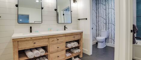 A modern bathroom with a wooden vanity, two mirrors, and a white toilet.