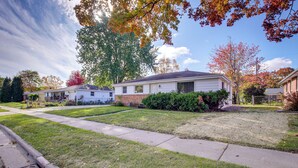 A suburban neighborhood with single-family homes, well-maintained lawns, and a clear sky.