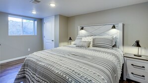 A bedroom with a bed, bedside tables, a window, and a door.