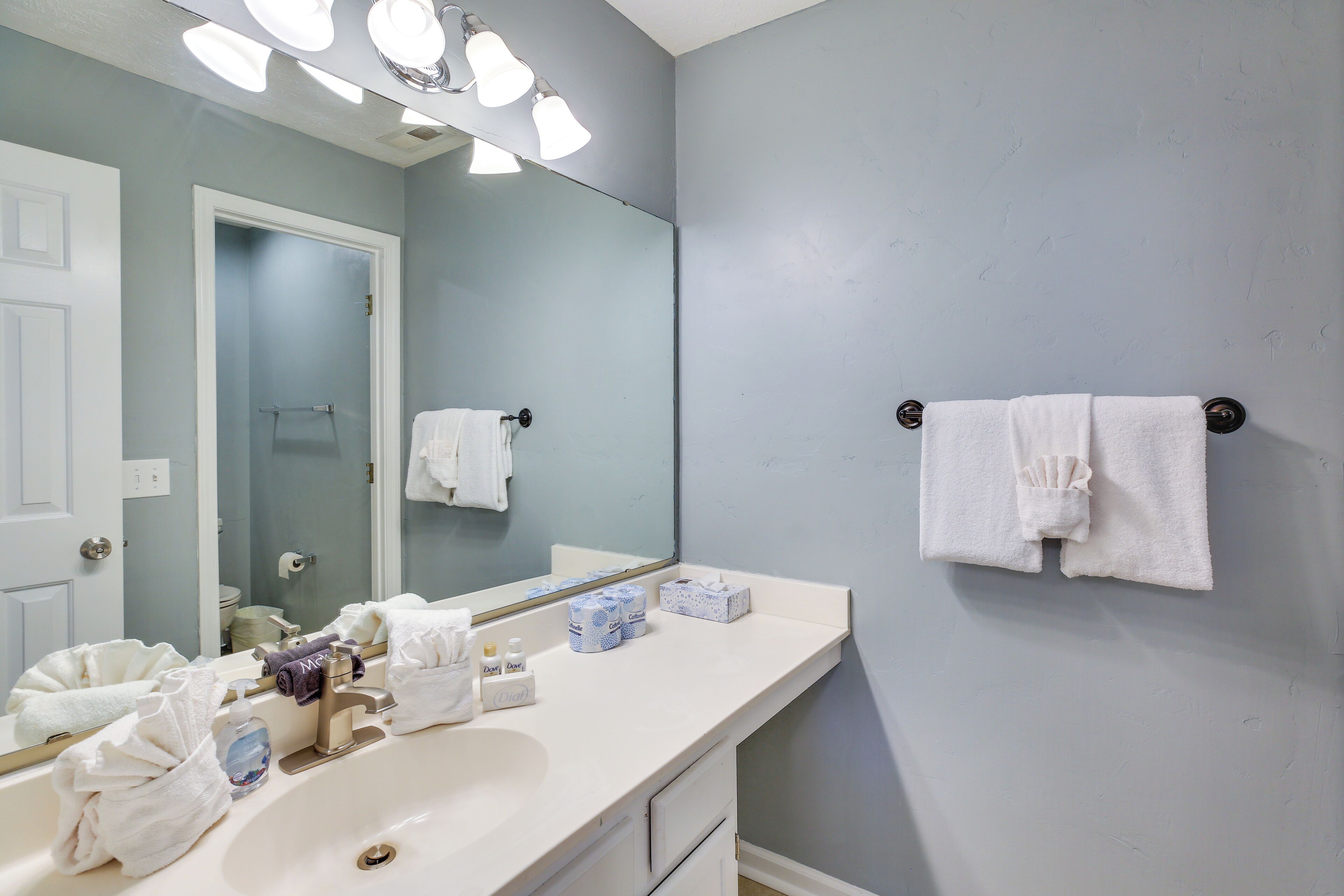 Un baño con lavamanos blanco, un espejo y un perchero para toallas.