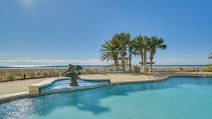 A swimming pool with a view of the ocean, palm trees, and a beach area with lounge chairs. - Perdido Key Condo w/ Ocean-view Balcony! (Pensacola)