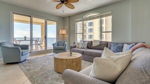 A spacious living room with a large sofa, two armchairs, a coffee table, and a ceiling fan. - Perdido Key Condo w/ Ocean-view Balcony! (Pensacola)
