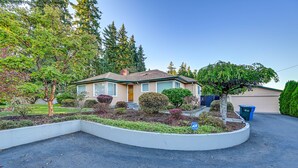 A two-story house with a front yard, a garage, and a driveway. - Enchanting Puyallup Home w/ Spacious Deck! (Puyallup)