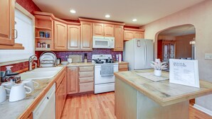 A kitchen with wooden cabinets, a white stove, a microwave, and a refrigerator. - Enchanting Puyallup Home w/ Spacious Deck! (Puyallup)