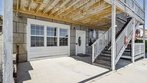 A building with a garage door, a staircase, and a door with a glass panel. - Mountain-view Deck: Stylish Virginia City Apt! (Virginia City)