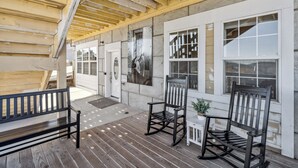 A covered porch with wooden flooring, rocking chairs, and a bench. - Mountain-view Deck: Stylish Virginia City Apt! (Virginia City)