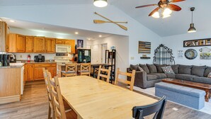A modern kitchen with wooden cabinets, a dining table, and a ceiling fan. - Riverfront Brookston Retreat w/ Deck & River Tubes (Brookston)