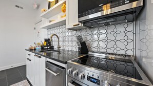 A modern kitchen with a stainless steel stove, oven, and built-in microwave. - Stylish Boutique Style Condo (Sandusky)