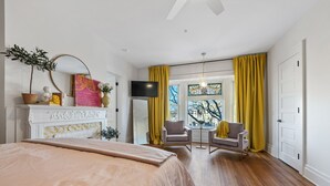 A bedroom with a bed, a fireplace, a TV, and a view of the outdoors through a window. - Stylish Boutique Style Condo (Sandusky)
