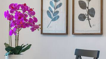 A dining area with a round table, a chair, and a potted orchid.
