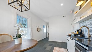 A modern kitchen with a black countertop, stainless steel appliances, and a window with a view of trees. - Stylish Boutique Style Condo (Sandusky)