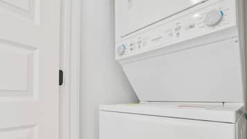 A white washing machine and dryer in a room with white walls and wooden flooring.