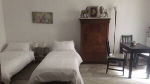 A room with two single beds, a wooden cabinet, a desk with a chair, and a floor lamp. - Vacances Romaines (Roma)