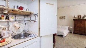 A compact kitchen with a sink, shelves, and a bed in the adjacent room. - Vacances Romaines (Roma)