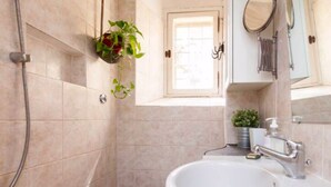 A bathroom with a shower, toilet, sink, and a small window. - Vacances Romaines (Roma)