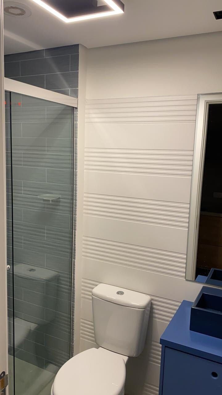 Casa de banho com cabine de chuveiro em vidro, sanita e toucador com lavatório.