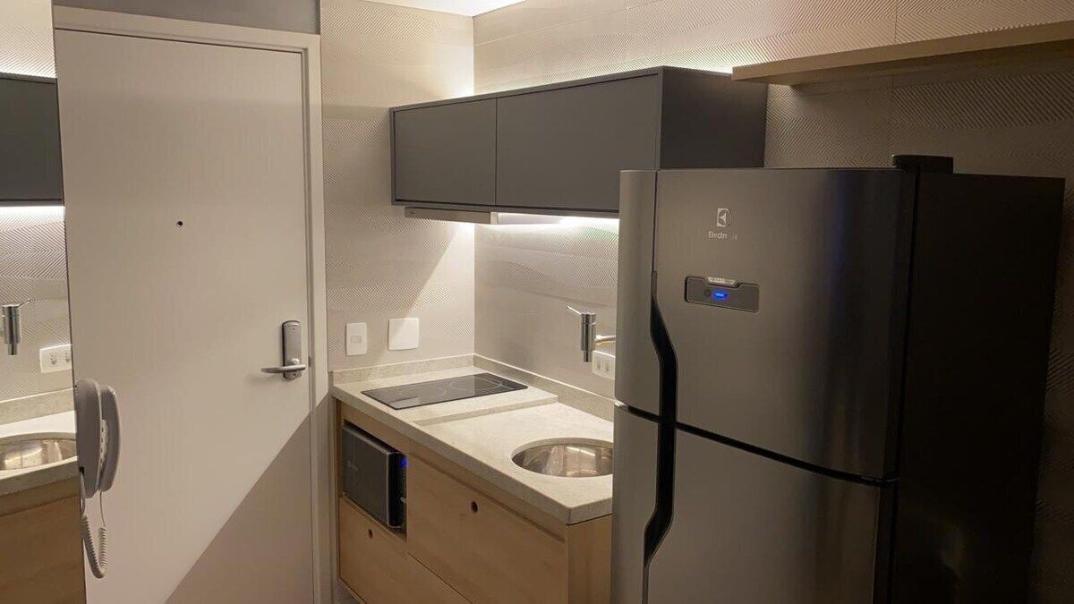 Een kleine keuken met een geïntegreerde koelkast, een magnetron en een spoelbak.