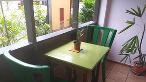 A small dining area with a table and two chairs, a potted plant, and a view of the outside. - HOSTAL HANSI BOCAS TOWN (Bocas del Toro)