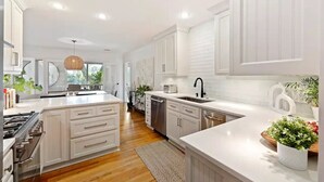 Una cocina moderna con armarios blancos, una isla central y un lavavajillas integrado.