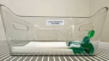 A clear plastic laundry basket with a label indicating it contains laundry detergent and dryer sheets.