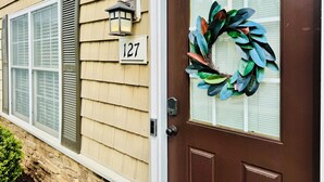 Una casa con puerta principal marrón, un adorno de lazo y el número 127.