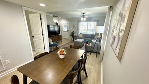 Un comedor con mesa de madera, sillas y un florero.