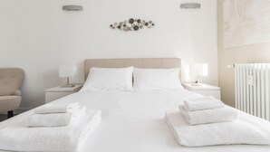 A hotel room with a bed, two nightstands, a chair, and a radiator. - Italianway - Vincenzo Monti 29 (Milan)