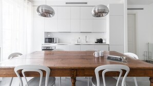 A modern kitchen with white cabinets, a wooden dining table, and two pendant lights. - Italianway - Vincenzo Monti 29 (Milan)