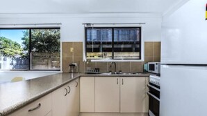 A modern kitchen with a large window, a microwave, and a refrigerator.